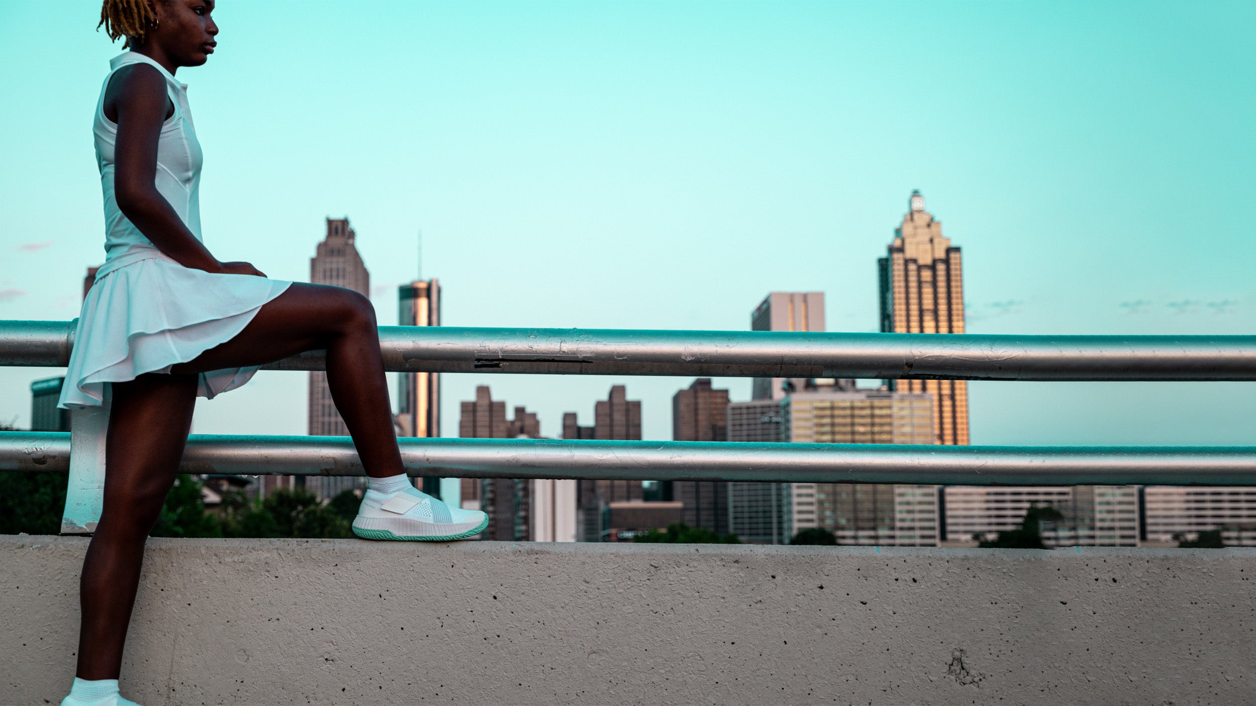 A young woman wearing The One standing in front of the Atlanta skyline.